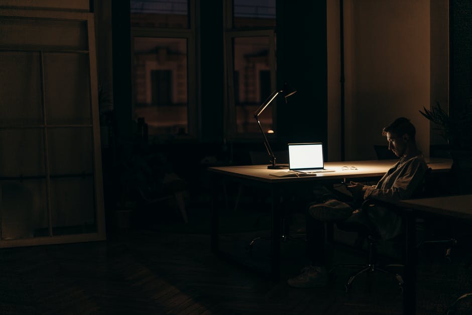 A person sitting at a desk with a laptop in a dark room